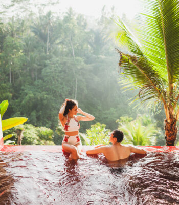 Young couple relaxing in luxury private infinity pool with amazing jungle view from above in Bali